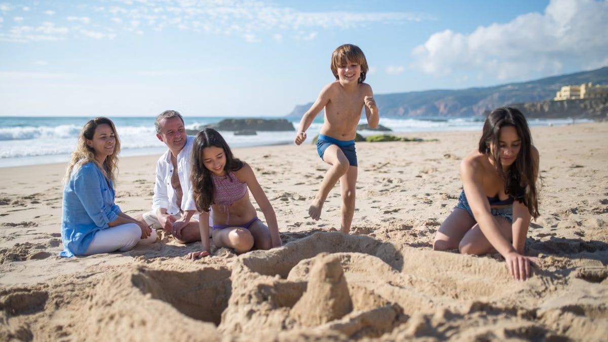 A family enjoys quality time and fun on a sunny beach, building sandcastles together.